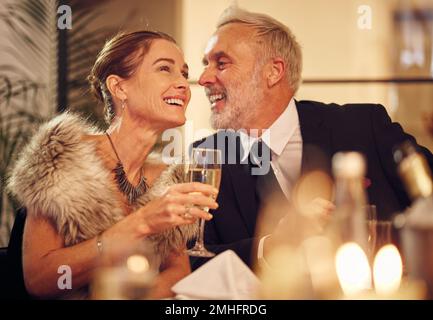 Glückliches, Senioren- und Pärchen-Abendessen mit Weinglas und Lächeln einer Frau mit lustigem Mann. Silvesterparty mit erwachsenen Gästen, die zusammen lächeln Stockfoto