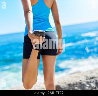 Die Vorteile des Dehnens sind vielfältig. Eine junge Frau, die sich vor ihrem Lauf dehnt. Stockfoto