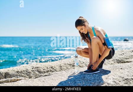 Machen Sie Gesundheit zu einer Priorität. Eine sportliche junge Frau, die sich beim Laufen ihre Schnürsenkel bindet. Stockfoto