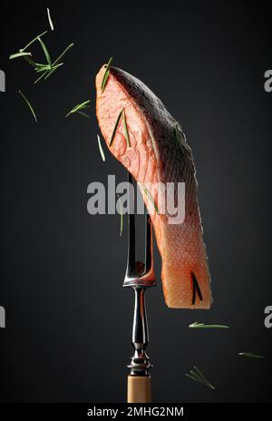 Gesmokter Lachs mit Rosmarin auf schwarzem Hintergrund. Stockfoto