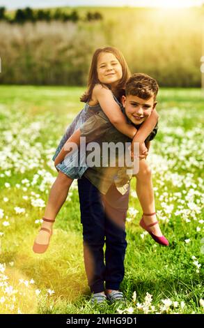 Große Brüder sind die Besten. Portrait eines süßen kleinen Jungen, der seine kleine Schwester mit dem Huckepack draußen mitnimmt. Stockfoto