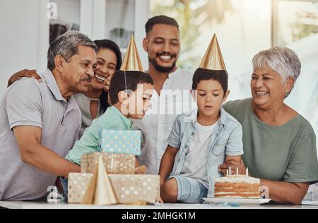Geburtstag, Feier und Zwillinge blasen die Kerzen auf einem Kuchen auf ihrer Party mit der Familie. Glücklich, aufgeregt und Kinder mit ihren Eltern und Stockfoto