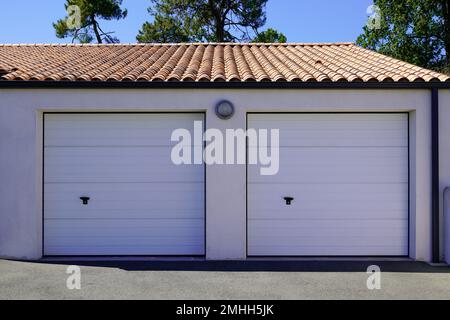 Garage mit doppeltem Querschnitt, geschlossen zwei weiße Türen am privaten Wohnhaus Stockfoto
