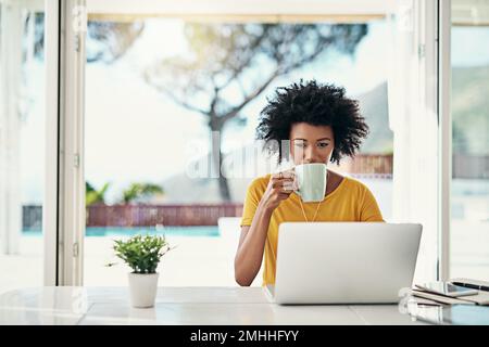 Die Arbeitszeit einplanen. Eine attraktive junge Frau, die zu Hause an ihrem Laptop arbeitet. Stockfoto