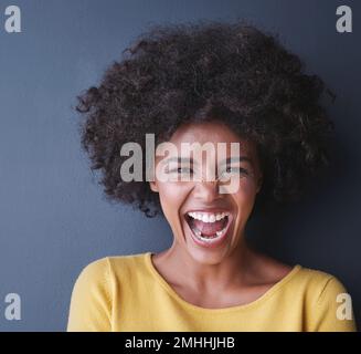 Ich bin so aufgeregt und ich kann es einfach nicht verbergen. Studiofoto einer attraktiven jungen Frau, die vor grauem Hintergrund posiert. Stockfoto