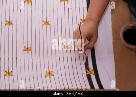 Eine Frau skizziert von Hand mit Kantenwerkzeugen und heißem Wachs, um traditionelle Batik herzustellen Stockfoto