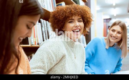 Freunde, Frauen und Schüler in der Bibliothek, Unterhaltung oder Glück beim Lernen, bei der Arbeit oder beim Fokussieren. Akademikerinnen, Mädchen oder Frauen Stockfoto