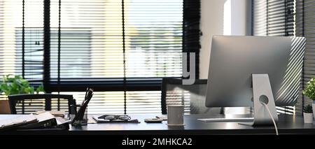 Moderne Büroeinrichtung mit Computer, Dokument und Topfpflanze auf einem leeren Holztisch Stockfoto