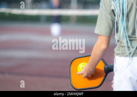 Nahspielerin Kind spielt Pickleball Spiel, Pickleball gelber Ball mit Paddel in den Händen, Outdoor Sport Freizeitaktivitäten für Kinder. Stockfoto