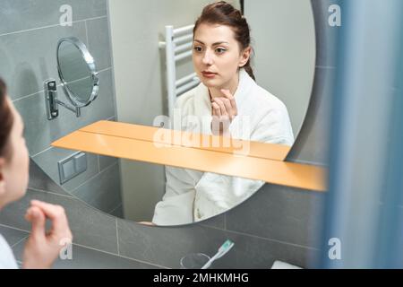 Junge Frau steht im Hotelbad vor dem Spiegel Stockfoto
