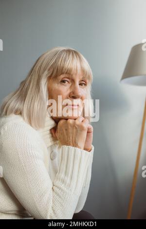 Porträt einer älteren Frau mittleren Alters, die sich auf einem bequemen Sofa entspannt und einen friedlichen Moment drinnen genießt. Stockfoto