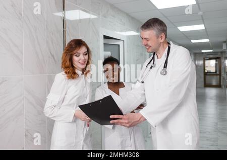 Eine Gruppe von Austauschärzten diskutiert die Diagnose im Krankenhauskorridor Stockfoto