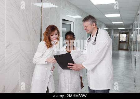 Eine Gruppe von Austauschärzten diskutiert die Diagnose im Krankenhauskorridor Stockfoto