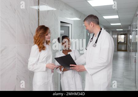 Eine Gruppe von Austauschärzten diskutiert die Diagnose im Krankenhauskorridor Stockfoto