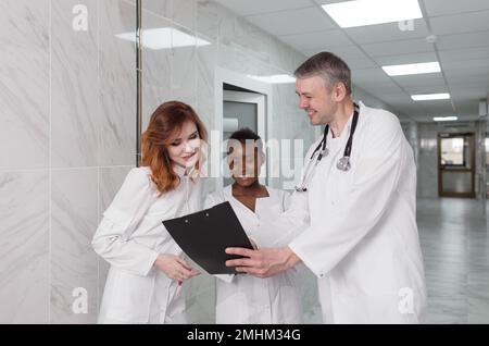 Eine Gruppe von Austauschärzten diskutiert die Diagnose im Krankenhauskorridor Stockfoto