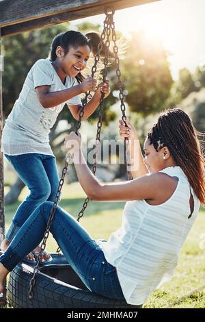 Ein weiterer Tag voller Spaß zusammen. Eine Mutter und ihre Tochter spielen zusammen auf einer Schaukel im Park. Stockfoto