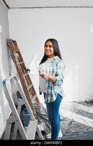 Eine junge indische Frau bereitet sich darauf vor, während eines Heimwerkerprojekts eine Wand zu streichen Stockfoto