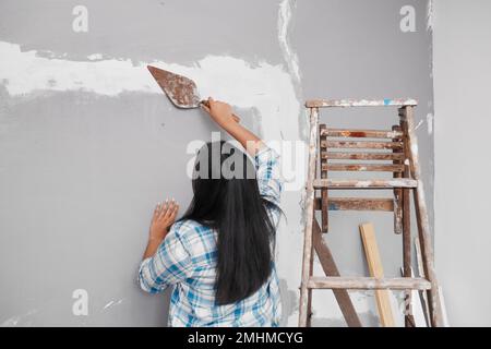 Junge Indianerin Pflaster über Risse im Heimwerkerprojekt Stockfoto