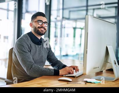 Hören Sie nie auf, sich zu fragen, was Sie erreichen können. Ein junger Designer, der an einem Computer in einem Büro arbeitet. Stockfoto
