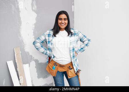 Porträt einer starken jungen Indianerin, die mit Werkzeuggürtel zu Hause Heimwerker machen will Stockfoto