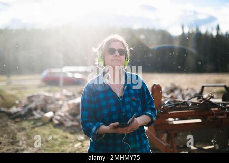 Reife Frau mit Ohrenschützer im Sägewerk Stockfoto