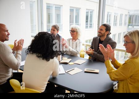 Geschäftsleute klatschen während einer Besprechung im Büro Stockfoto