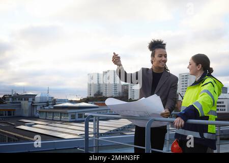 Architekten reden, während sie Baupläne halten Stockfoto