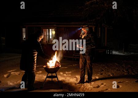 Mann und Frau beleuchten im Winter den Grill Stockfoto