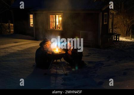 Mann und Frau beleuchten im Winter den Grill Stockfoto