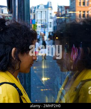 Seitenansicht einer Frau, die durch das Fenster in der Stadt schaut Stockfoto