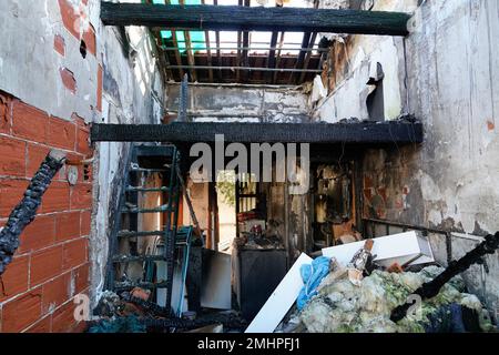 Verbrannte Innenausstattung des Wohnzimmers mit Wänden Möbel und Boden aus Asche und Kohle zerstörten das alte Gebäude nach dem Feuer Stockfoto