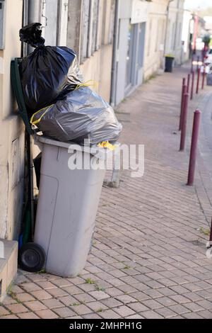 Rollender Mülltonnen überläuft Tasche grauer Wheelie in der Stadt Stockfoto