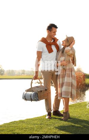 Ein junges Paar mit Picknickkorb in der Nähe des Sees an sonnigen Tagen Stockfoto