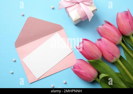 Flach liegend mit Tulpen und Karte auf hellblauem Hintergrund, Platz für Text. Alles gute zum Muttertag Stockfoto