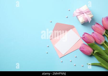 Flach liegend mit Tulpen und Karte auf hellblauem Hintergrund, Platz für Text. Alles gute zum Muttertag Stockfoto