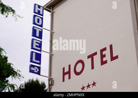 Blaues und rotes Schild mit Pfeil und drei Sternen auf dem Gebäude in Touristenstadt Stockfoto