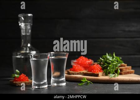Kalter russischer Wodka und Sandwiches mit rotem Kaviar auf schwarzem Tisch Stockfoto