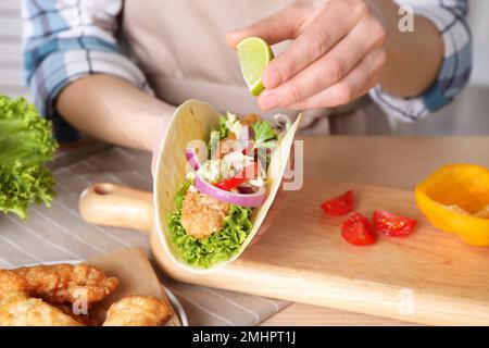 Eine Frau, die Limette auf Fisch-Taco am Tisch presst, Nahaufnahme Stockfoto