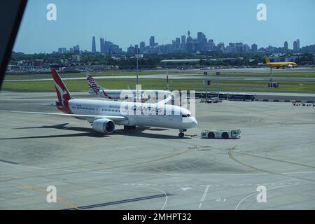 Qantas Airways Flug bereitet sich auf den Abflug vom Kingsford Smith Airport vor, mit Sydney Skyline in Ferne, Australien. Stockfoto