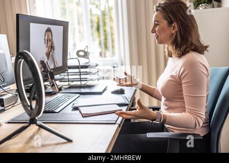 Bildschirmansicht einer Frau, die Online-Kundenservice für das Büro eines Mitarbeiters bereitstellt. Eine Geschäftsfrau gibt ein Online-Interview mit ihrem Klienten. Stockfoto