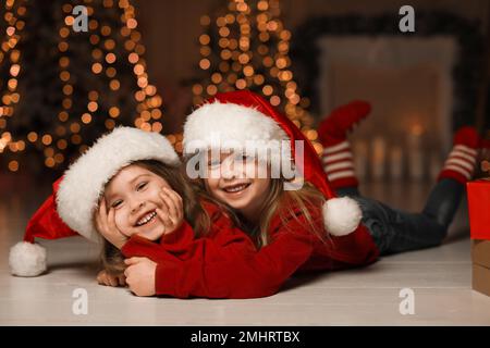 Süße kleine Kinder, die zu Hause Weihnachtsmannmützen tragen. Weihnachtszeit Stockfoto