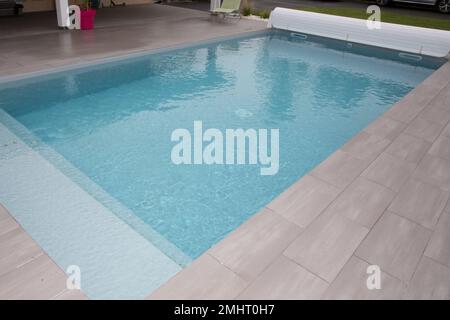 Swimming Pool im Gartenhaus mit starrer Poolabdeckung auf Rolle aufgerollt Stockfoto