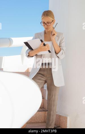 Junge blonde Geschäftsfrau, die über neue Projektideen nachdenkt. Stockfoto