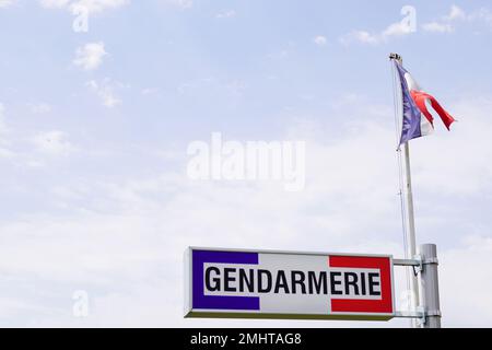 Gendarmerie, französisches Militärpolizeizeichen und französische Flagge am bewölkten Himmel Stockfoto