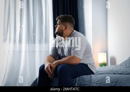 Deprimierter übergewichtiger Mann im Bett zu Hause Stockfoto