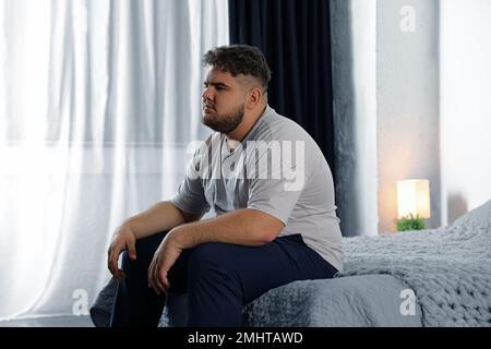 Deprimierter übergewichtiger Mann im Bett zu Hause Stockfoto