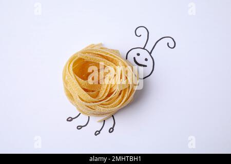 Lustige Wanze mit Tagliatelle-Pasta auf weißem Hintergrund, Draufsicht Stockfoto