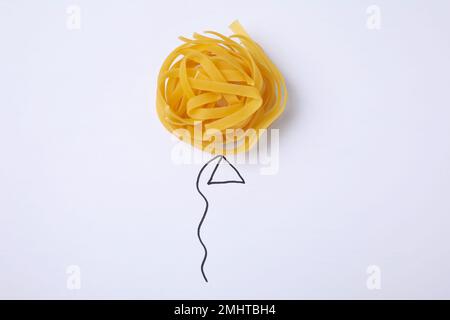 Ballon mit Tagliatelle-Pasta auf weißem Hintergrund, Draufsicht Stockfoto