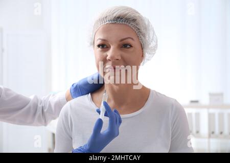 Reife Frau mit doppeltem Kinn, die in der Klinik injiziert wird Stockfoto