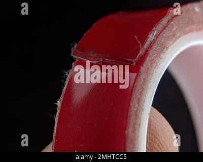 Rotes doppelseitiges Nahklebeband auf schwarzem Hintergrund. Stockfoto